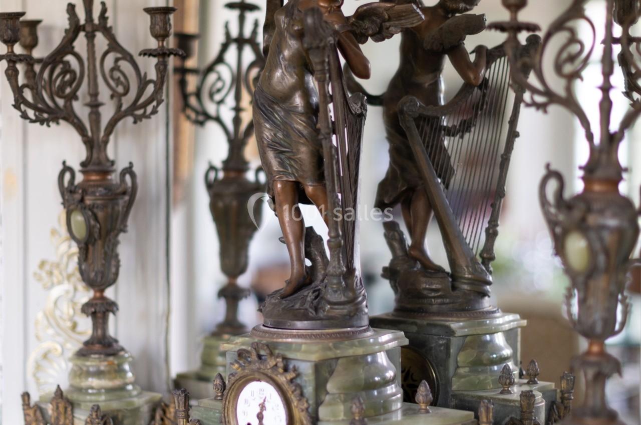 Statue en bronze représentant deux figures féminines avec des candélabres et une horloge sur une cheminée ornée.