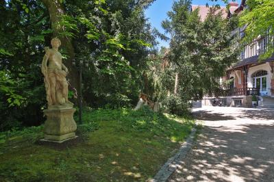 Cuisine professionnelle avec plans de travail en inox, réfrigérateurs, sol en bois clair et murs carrelés gris.