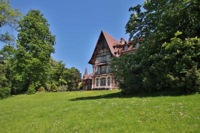 Cuisine professionnelle avec plans de travail en inox, réfrigérateurs, sol en bois clair et murs carrelés gris.