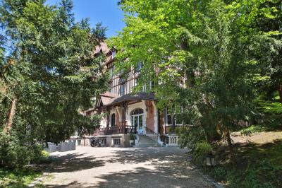 Cuisine professionnelle avec plans de travail en inox, réfrigérateurs, sol en bois clair et murs carrelés gris.