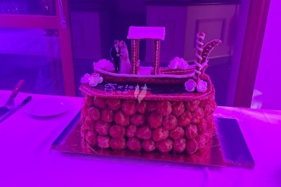 Salle décorée avec rideaux bleus, guirlandes lumineuses, vases avec fleurs et table recouverte d'une nappe blanche.