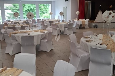 Salle décorée avec rideaux bleus, guirlandes lumineuses, vases avec fleurs et table recouverte d'une nappe blanche.