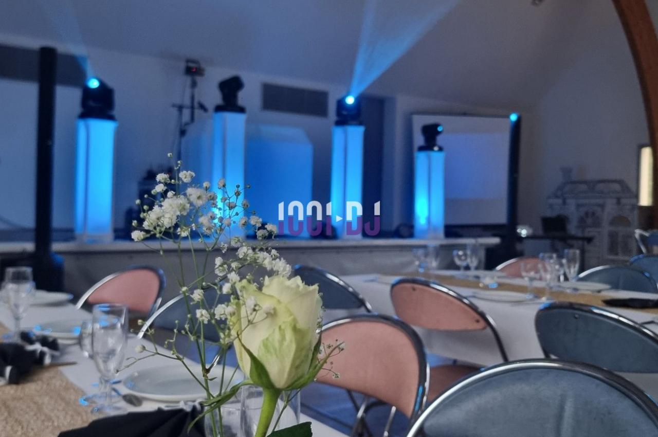 Salle de réception décorée avec des tables dressées et un éclairage bleu mettant en valeur une scène.