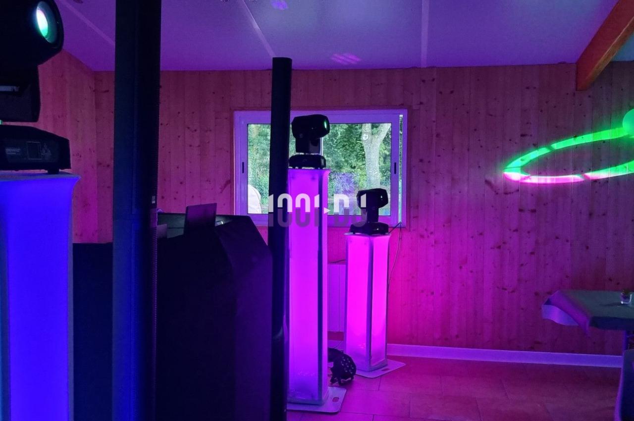 Équipements d'éclairage coloré dans une salle en bois, avec des tables dressées et des effets lumineux projetés.