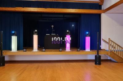 Équipements d'éclairage coloré dans une salle en bois, avec des tables dressées et des effets lumineux projetés.
