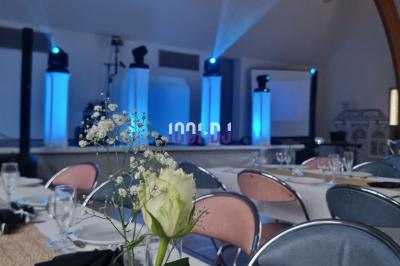 Équipements d'éclairage coloré dans une salle en bois, avec des tables dressées et des effets lumineux projetés.