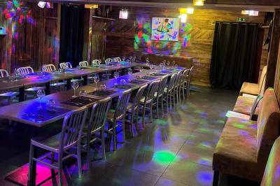 Salle de restaurant avec longues tables dressées, éclairage tamisé et effets lumineux colorés sur le sol.