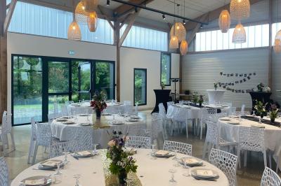 Centre de table floral avec roses blanches sur un support doré, dans une salle lumineuse avec grandes baies vitrées.