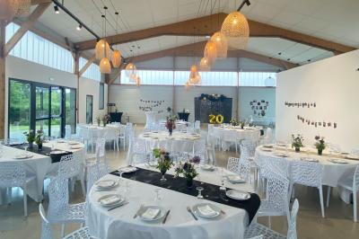 Centre de table floral avec roses blanches sur un support doré, dans une salle lumineuse avec grandes baies vitrées.