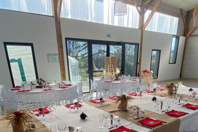 Centre de table floral avec roses blanches sur un support doré, dans une salle lumineuse avec grandes baies vitrées.