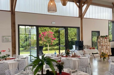 Centre de table floral avec roses blanches sur un support doré, dans une salle lumineuse avec grandes baies vitrées.