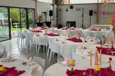 Centre de table floral avec roses blanches sur un support doré, dans une salle lumineuse avec grandes baies vitrées.