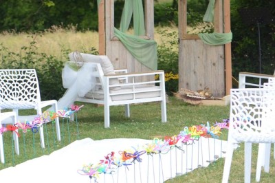 Centre de table floral avec roses blanches sur un support doré, dans une salle lumineuse avec grandes baies vitrées.