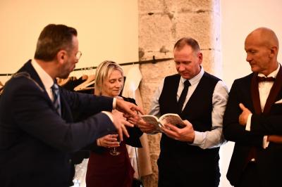 Un homme en costume effectue un tour de magie avec des cartes devant un petit groupe de personnes souriantes.