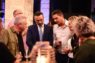 Un homme en costume effectue un tour de magie avec des cartes devant un petit groupe de personnes souriantes.