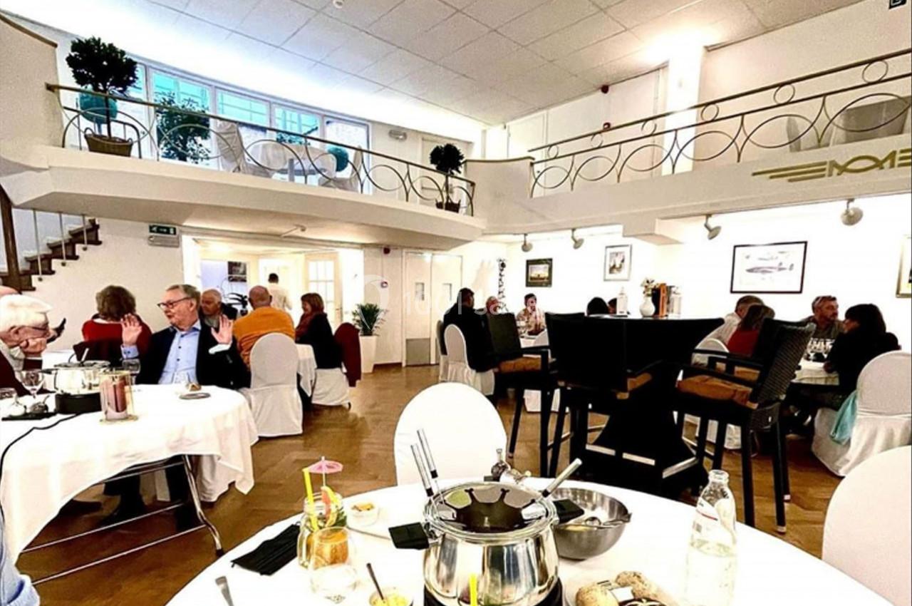 Salle de restaurant lumineuse avec des convives assis à des tables, ambiance conviviale et décor élégant.