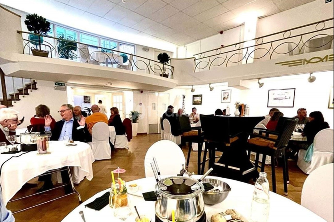 Salle de restaurant lumineuse avec des convives assis à des tables, ambiance conviviale et décor élégant.