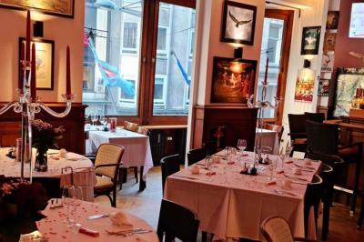 Salle de réception lumineuse avec tables rondes dressées, chaises blanches et éclairage violet au plafond.