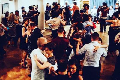 Intérieur d'un café lumineux avec canapés colorés, grandes fenêtres donnant sur une rue et un bar en arrière-plan.