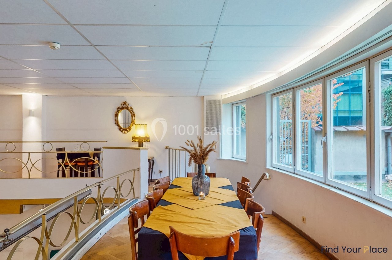 Salle à manger lumineuse avec une grande table rectangulaire, des chaises en bois et une décoration sobre.