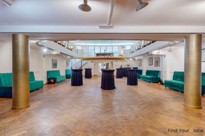 Intérieur d'un café lumineux avec canapés colorés, grandes fenêtres donnant sur une rue et un bar en arrière-plan.