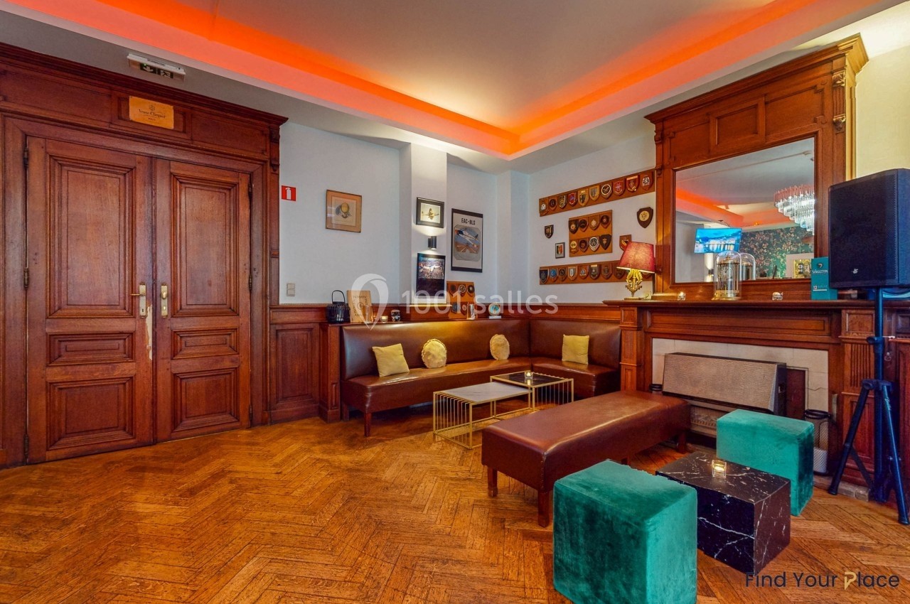 Salon chaleureux avec parquet, mobilier en bois, banquettes, tables basses et décorations murales.