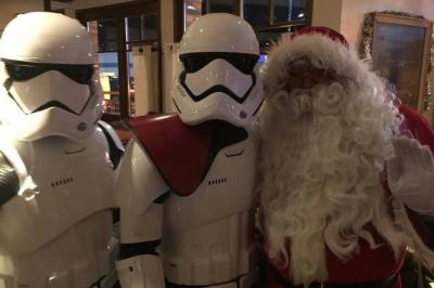 Salle de réception décorée avec des tables rondes, nappes blanches, éclairage rouge et arrangements floraux suspendus.