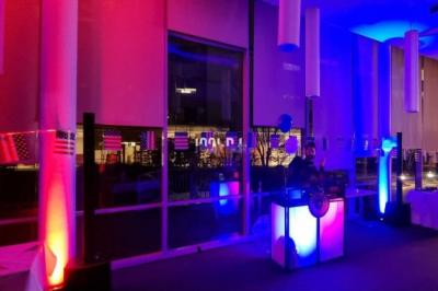 Salle de fête animée avec éclairage rouge, plafond texturé et personnes discutant ou dansant.