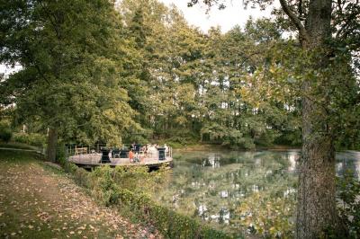Vue d'un parc verdoyant avec des arbres, une pelouse et une rivière au premier plan, sous un ciel clair.
