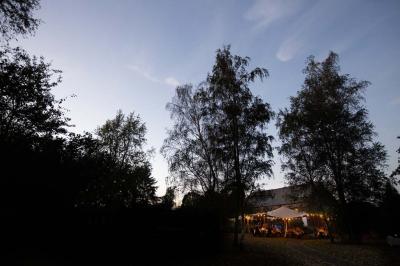 Vue d'un parc verdoyant avec des arbres, une pelouse et une rivière au premier plan, sous un ciel clair.