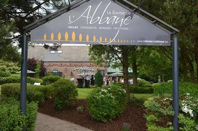 Vue d'un parc verdoyant avec des arbres, une pelouse et une rivière au premier plan, sous un ciel clair.