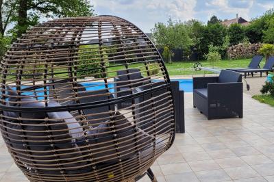 Jardin en soirée avec des arbustes fleuris, éclairé par des lampes au sol, entouré d'arbres et de végétation.