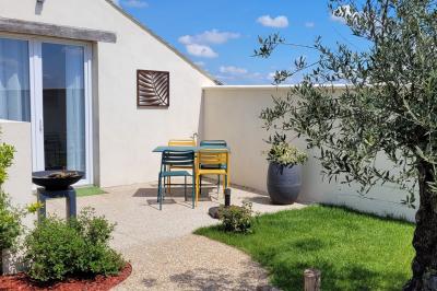 Jardin en soirée avec des arbustes fleuris, éclairé par des lampes au sol, entouré d'arbres et de végétation.