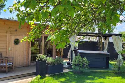 Jardin en soirée avec des arbustes fleuris, éclairé par des lampes au sol, entouré d'arbres et de végétation.