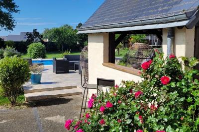 Jardin en soirée avec des arbustes fleuris, éclairé par des lampes au sol, entouré d'arbres et de végétation.