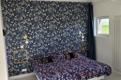 Jardin en soirée avec des arbustes fleuris, éclairé par des lampes au sol, entouré d'arbres et de végétation.