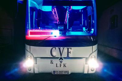 Intérieur d'un autocar avec sièges rouges, éclairage tamisé et allée centrale recouverte d'un tapis rouge.