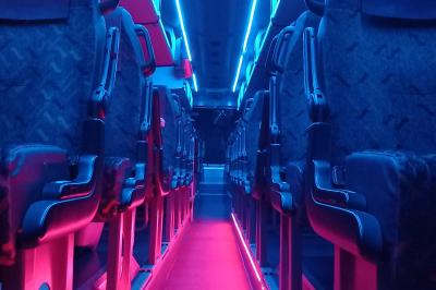 Intérieur d'un autocar avec sièges rouges, éclairage tamisé et allée centrale recouverte d'un tapis rouge.