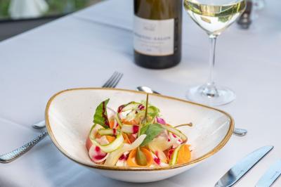 Vue aérienne d'un bâtiment moderne entouré d'arbres et d'une pelouse, avec un coucher de soleil en arrière-plan.