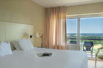 Vue aérienne d'un bâtiment moderne entouré d'arbres et d'une pelouse, avec un coucher de soleil en arrière-plan.