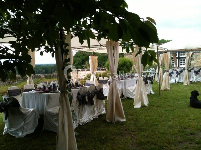 Tables décorées sous des tonnelles blanches dans un jardin, avec des nappes et chaises habillées pour un événement en plein…