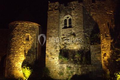 Vue nocturne d'un château en pierre éclairé par des projecteurs, mettant en valeur ses murs et ses fenêtres.