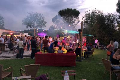 Deux fauteuils en osier blanc entourés de décorations florales et de voilages, installés sur une pelouse verdoyante.