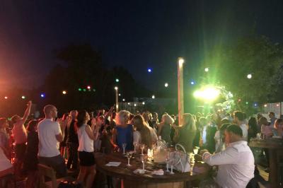 Deux fauteuils en osier blanc entourés de décorations florales et de voilages, installés sur une pelouse verdoyante.