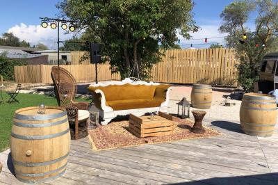 Deux fauteuils en osier blanc entourés de décorations florales et de voilages, installés sur une pelouse verdoyante.