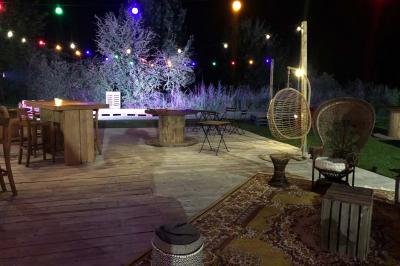 Deux fauteuils en osier blanc entourés de décorations florales et de voilages, installés sur une pelouse verdoyante.