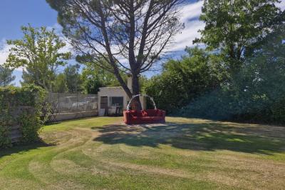 Deux fauteuils en osier blanc entourés de décorations florales et de voilages, installés sur une pelouse verdoyante.