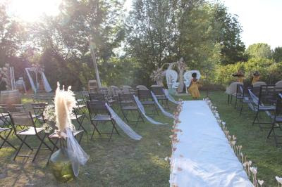 Deux fauteuils en osier blanc entourés de décorations florales et de voilages, installés sur une pelouse verdoyante.