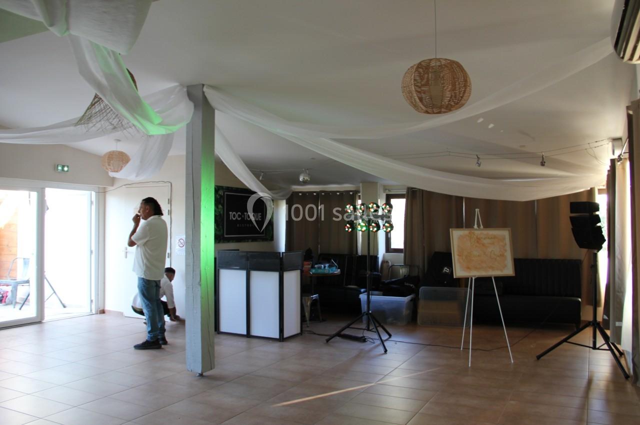 Un homme debout dans une salle lumineuse avec des décorations suspendues et un bar en arrière-plan.