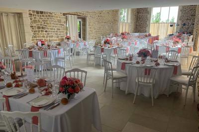 Salle en pierre décorée avec des cadres photo, des chaises blanches et des bougies sur une table.
